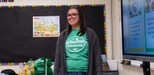 Volunteer in an early years classroom presenting at the front of the room and smiling at students off-camera